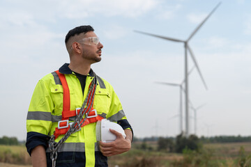 Male windmill engineer wearing uniform hold helmet safety standing at wind turbine farms for generating renewable energy. © Supachai