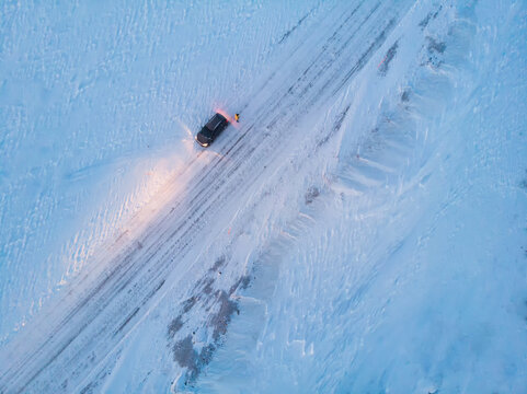 A girl in a blue dress walks along the shore of a salt lake with mirrored sky and clouds at sunset