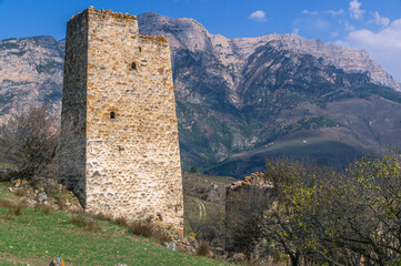 An ancient stone city in the Republic of Ingushetia. Historical structures for protection from attacks.   Fortress towers made of stones against the background of mountains and blue sky.