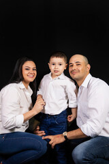 Portrait of a happy family, all wearing white shirts on a black background.