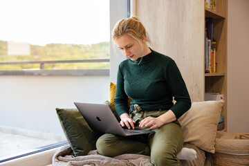 Women's remote work wellness. Work-life balance for women. A woman using laptop in the coziest place.