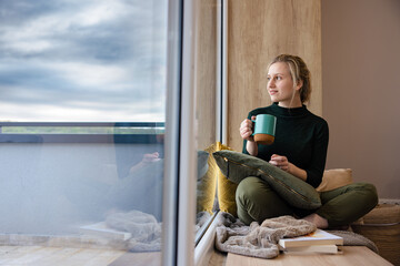 Beautiful girl drinks coffee by the window. Me-time. Time for relaxation.