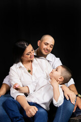 Parents sitting looking at their child on a black background.