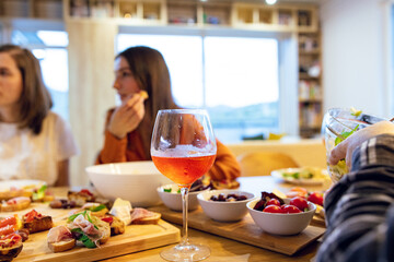 People eating at the table with the focus on the glass of wine