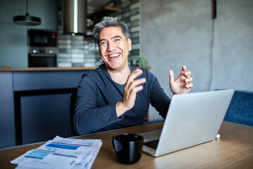 Middle aged man working on his laptop and going over his bills at home