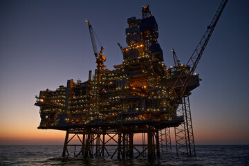 Offshore oil and gas jack-up platform in the sea at sunset. 