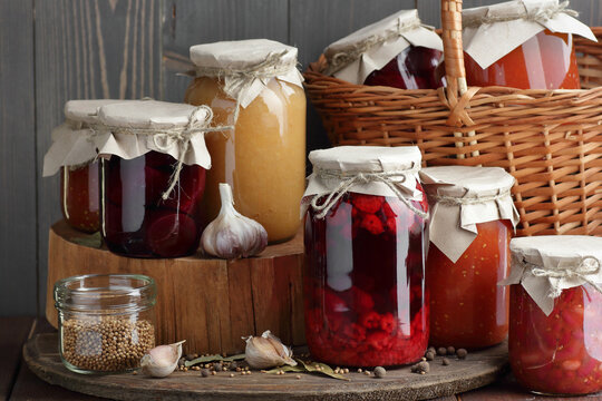 Homemade canned vegetable food: conserved beetroot, tomato paste, preserved bean, jam, pickles on wooden rustic background, canning of food, vegetable fermentation and marination concept - Powered by Adobe