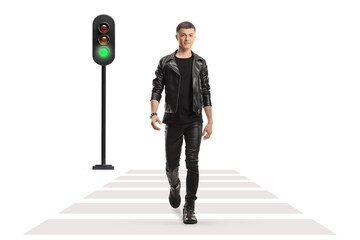 Full length portrait of a guy in a leather jacket and pants walking at pedestrian crosswalk