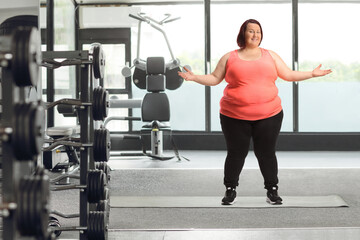 Fototapeta na wymiar Cheerful overweight woman in sportswear posing in a gym