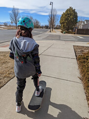 Young girl skateboarding on a sidewalk while wearing a helmet.