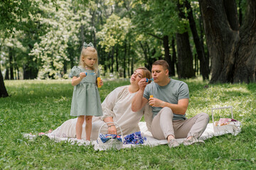 happy family relaxing outdoors in the park dad and daughter blowing soap bubbles Fun and carefree childhood family weekend