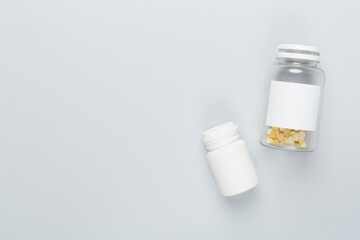 Plastic bottles with vitamins on color background, top view