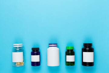 Plastic bottles with vitamins on color background, top view