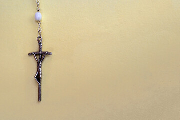 The cross on a rosary on a yellow background. With space for text.