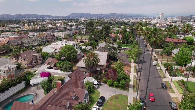 Drone aerial establishing shot from West Hollywood upper class neighborhood and rich homes looking towards Hollywood sign and film industry town outside Los Angeles