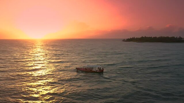 Wonderful Maldivian boat Dhoni on tropical blue sea, taking tourist to a sunset cruise. Aerial drone view 4K.