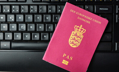 Danish. passport on a laptop keyboard. Online registration. Immigration control verifies passport identification data.
