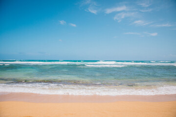 Fototapeta na wymiar The sand and water of Wailua Beach on the island of Kauai, Hawaii on a clear blue day with no people