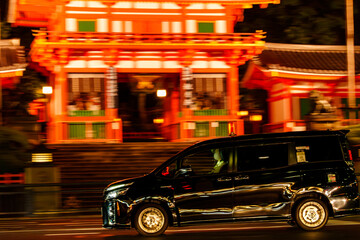 京都の夜の街を走る黒塗りのタクシー