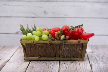 Wooden basket with fresh fruits and vegetables on a wooden table. Fresh and healthy food concept. Raw vegetarian food.
