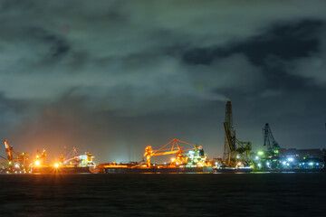 海辺の工業地帯に停泊するタンカーと工場夜景
