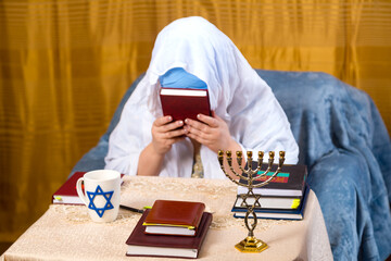 A Jewish woman in a Kisui Rosh headdress and a prayer veil kisses the siddur.