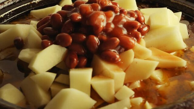 In cholent chicken and potatoes in spices, beans in tomato sauce fall. close-up
