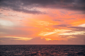 Naklejka na ściany i meble Beautiful pastel pink and orange sunset over the ocean near the Na Pali coastline on the island of Kauai, Hawaii