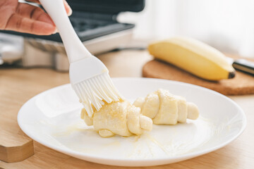 Butter the croissant dough. to prepare for making croffles.