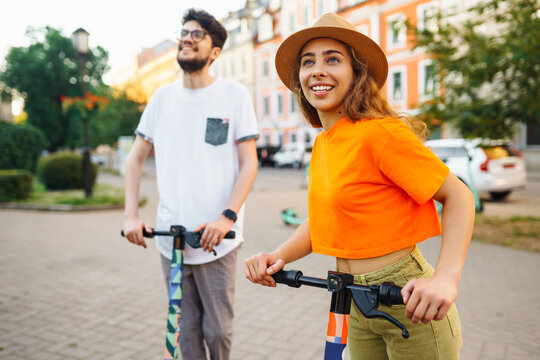 Young couple having fun driving electric scooter through the city. Active life. Ecological transportation concept. - Powered by Adobe
