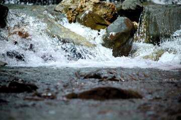 Fototapeta na wymiar Water flowing over river rocks near mountains in Nathia Gali, Abbottabad, Pakistan.
