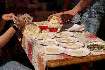 The girls knead the dough and cut out figures of various shapes. The process of making cookies or shortbread.