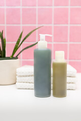 Fototapeta na wymiar Pink Tile Bathroom with Plant, Towels, and Skincare Bottles