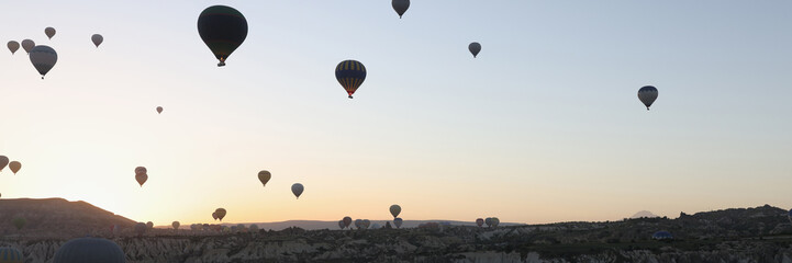 Panoramic banner landscape with hot air balloons black silhouette rising into the sky with sunrise