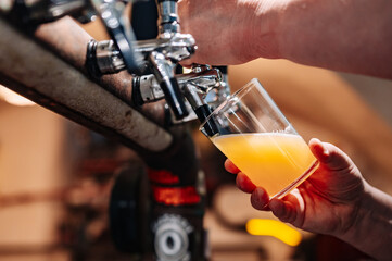 man bartender hand at beer tap pouring beer in glass in bar or pub