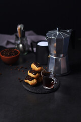 Chocolate eclairs with a cup of coffee and a coffee pot