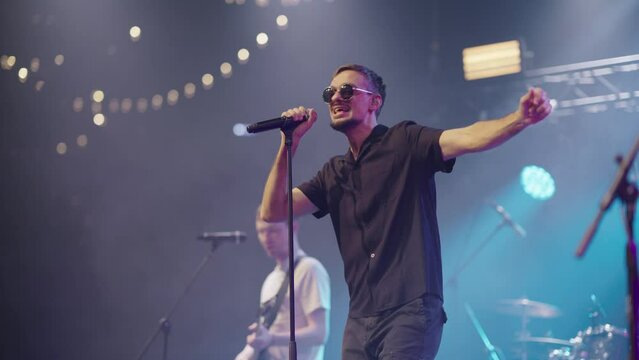 Soloist and backing vocalist with guitar perform on stage in nightclub. Slow motion