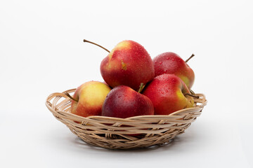 Red wet apples in a wicker plate on a white background