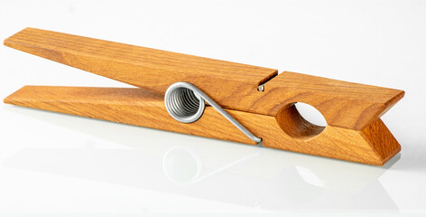 Large wooden clothespin in a bright color with a reflection in a white mirror background