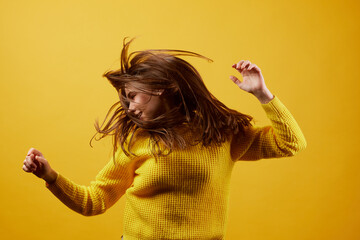 girl in a yellow sweater dancing on a yellow background