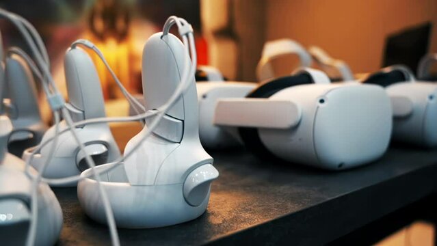 Close view of multiple white VR controllers and headsets on a table. Slow motion