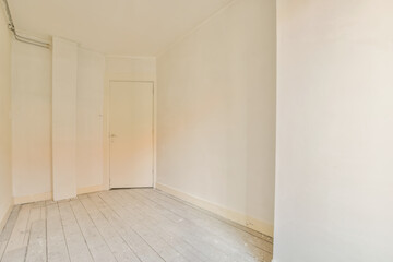 an empty room with white walls and wood flooring on one side, there is a door to the left