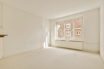 an empty living room with white walls and floor to the right there is a fire place in front of the window