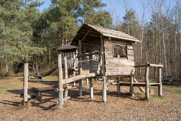 Wooden playground for children with play house, climbing frame and a slide in the park