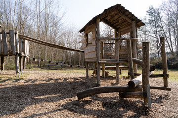 Fototapeta na wymiar Playground for children with a wooden play house and a bridge in the nature park