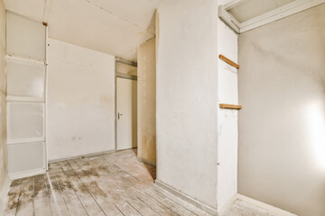 an empty room with white walls and wood flooring on the right hand side, there is a door that leads to another room