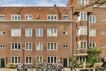 Obraz premium an apartment building with bicycles parked in the street next to each other buildings on a sunny day - stock photo