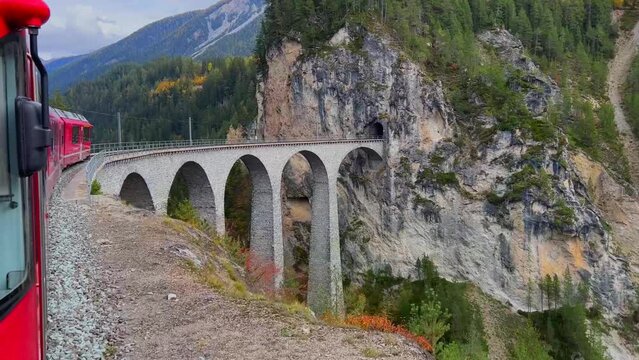 Bernina train passing the bridge  between two mountains in Swill alps Switzerland