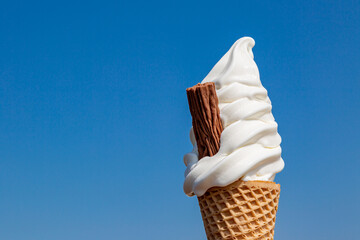An ice cream cone against a clear blue sky, with space for text