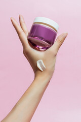 Hand Holding Purple Jar of Cream with Smear